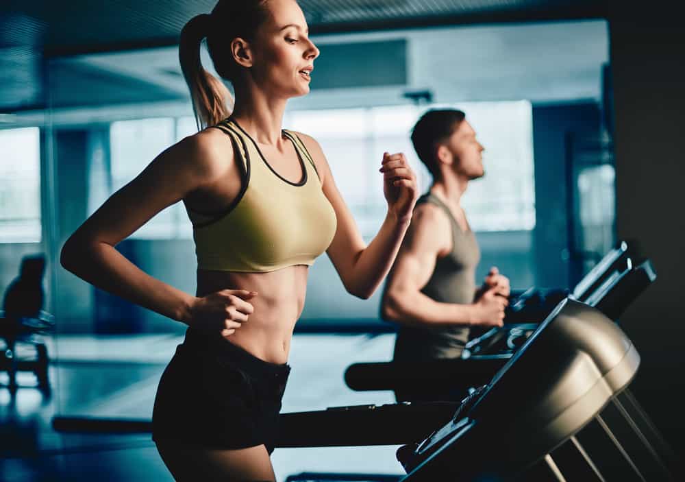 cardio-tabla-gimnasio chico y chaica corriendo en la cinta del gimnasio
