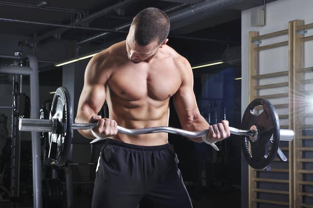 biceps-curl-rutinas-gimnasio hombre haciendo biceps curl con barra Z en el gimnasio